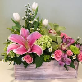 Pink lilies and roses in a wooden box with mixed blooms