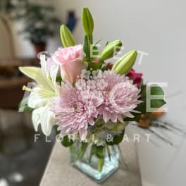 Pink chrysanthemums and lilies in a clear glass vase