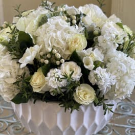 Low white and ivory flower arrangement in a textured white bowl