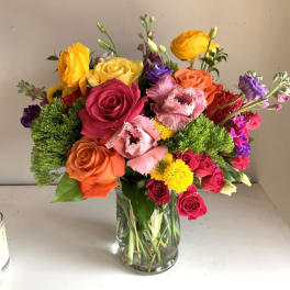 Colorful mixed bouquet of roses and other blooms in a clear glass vase
