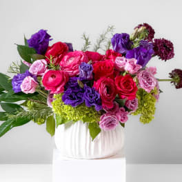Bouquet of pink, red, and purple flowers in a white vase