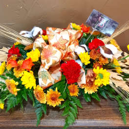 Autumn floral arrangement with yellow and red flowers and a leaf-patterned bow