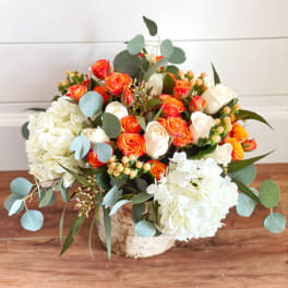 Bouquet of orange and white roses with white hydrangeas in a rustic container