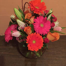 Bright mixed bouquet in a glass vase with gerbera daisies, roses, and lilies