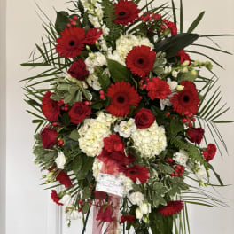 Standing floral spray with red gerberas and roses, white hydrangeas, and greenery