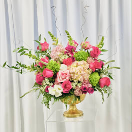 Pink and green floral arrangement in a gold pedestal vase