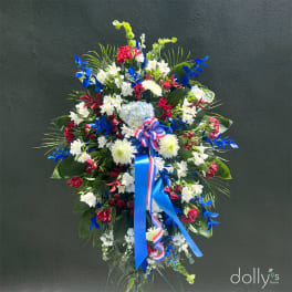 Large standing floral spray with red, white, and blue flowers and ribbon