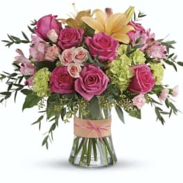 Pink and yellow flower bouquet in a clear glass vase