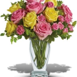 Pink and yellow roses arranged in a clear glass vase