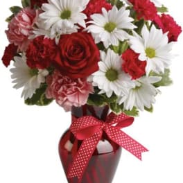 Red roses and white daisies in a red vase with a polka-dot ribbon