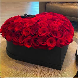 Heart-shaped black box filled with tightly packed red roses on a round table