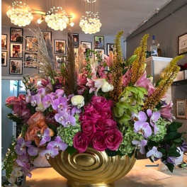 Large floral arrangement with pink roses and purple orchids in a gold vase