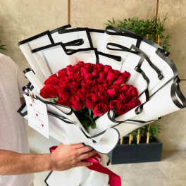 Bouquet of red roses wrapped in white paper with black trim