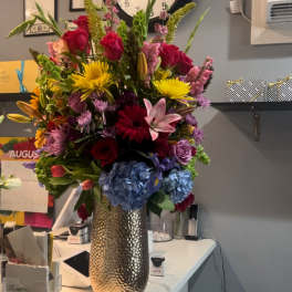 Tall mixed bouquet in a metallic vase with roses, lilies, and hydrangeas