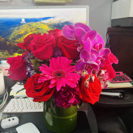 Pink and red flower arrangement in a green vase