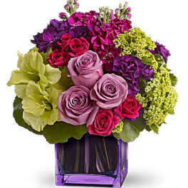 Purple and pink roses with green blooms in a purple glass vase