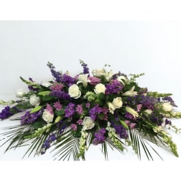Low floral arrangement with white roses, lilies, and purple blooms