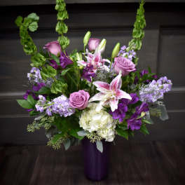 Purple and white floral arrangement in a tall vase