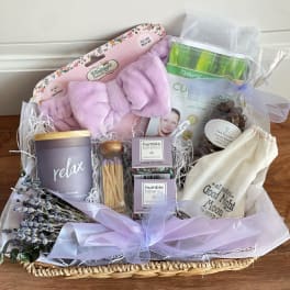 Gift basket with a lavender blanket, candle, soap, bath items, and chocolates