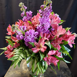 Pink and purple flowers arranged in a clear glass vase