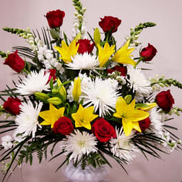 Large bouquet of red roses, yellow lilies, and white spider mums in a white vase