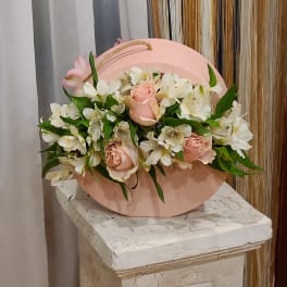 Pink roses and white lilies arranged in a round pink box