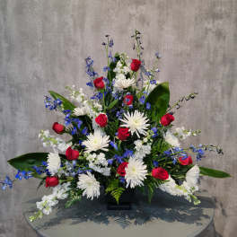 Red roses, white daisies, and blue flowers in a black vase