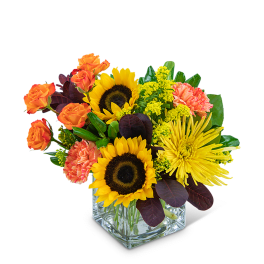 Sunflowers, orange roses, and yellow chrysanthemums in a square glass vase