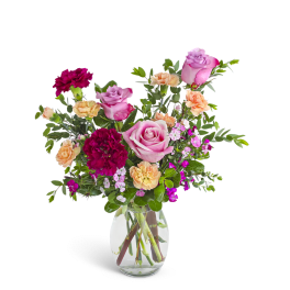 Mixed bouquet of pink roses, red and peach carnations in a clear glass vase.