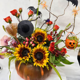 Halloween floral arrangement in a pumpkin container with sunflowers and roses