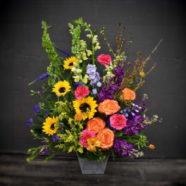 Colorful mixed flower arrangement in a gray vase with sunflowers and roses
