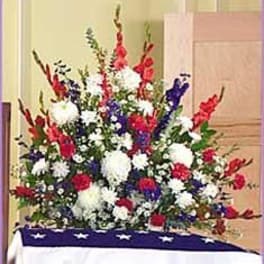Patriotic red, white, and blue sympathy arrangement in front of a star-draped cloth