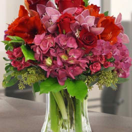 Lush red and pink flower arrangement in a clear glass vase