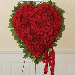 Heart-shaped arrangement of red roses with a red ribbon