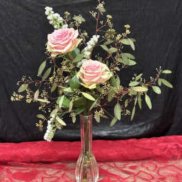 Pink roses in a clear glass vase with airy greenery