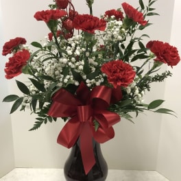 Red carnations in a black vase with a red ribbon bow