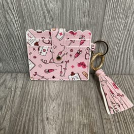 Pink patterned card holder with a tassel keychain on a wood surface