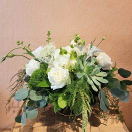 White roses and succulents in a low arrangement with greenery