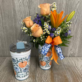 Peach roses and orange lilies in a pumpkin-patterned tumbler with ribbon