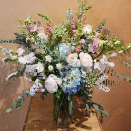 Pastel bouquet of roses, hydrangeas, and orchids in a glass vase