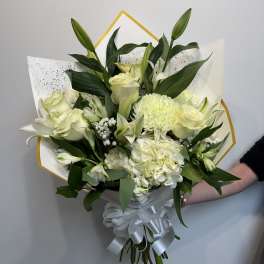 White bouquet with lilies, roses, and hydrangea wrapped in white paper