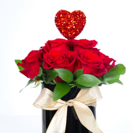 Red roses in a black vase with a glittery heart topper and gold ribbon