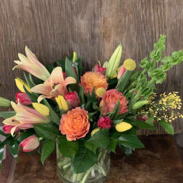 Mixed bouquet of lilies, roses, and tulips in a glass vase