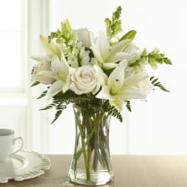 White lilies and roses arranged in a clear glass vase.