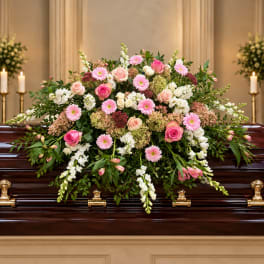 Large pink and white floral spray on a dark casket