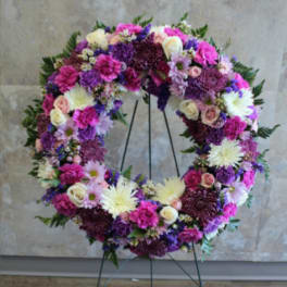 Large floral wreath on a stand with pink, purple, and white blooms