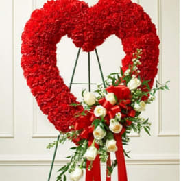 Heart-shaped red floral wreath with white roses and a red ribbon bow