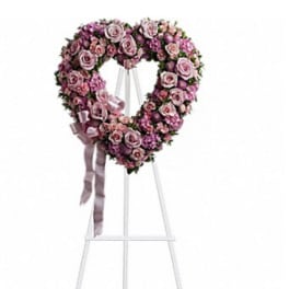 Heart-shaped pink and lavender rose wreath on an easel with ribbon