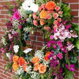 Large floral wreath with orange, pink, and white flowers on a stand