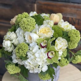 White and green floral arrangement in a round box